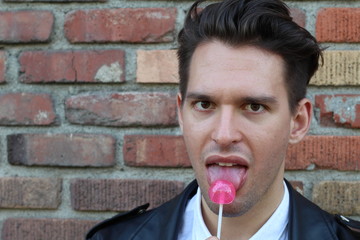Silly man licks the glass instead of his lollipop in this funny childish photo
