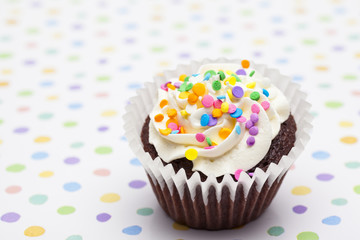 brown cupcake decorated with cream and sprinkles.