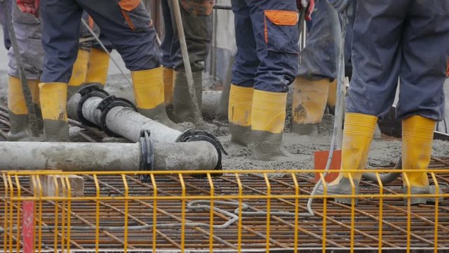 Workers in yellow safety boots pouring liquid concrete.