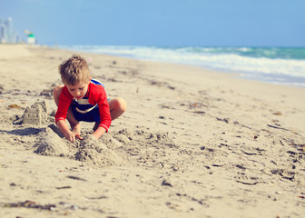 little boy play with sand on summer beach