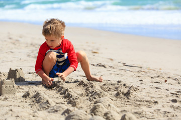 little boy play with sand on summer beach