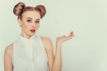 Close-up portrait of surprised beautiful girl with funny hairstyle with open hand and open-mouthed. 