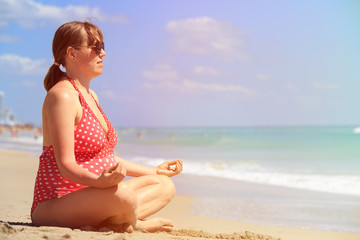 Fototapeta na wymiar Pregnant woman practicing yoga at beach