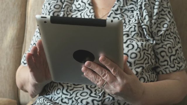 An old woman viewing photos using a digital tablet
