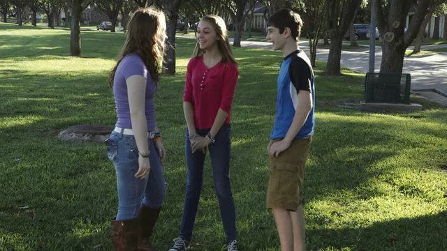 A teenage boy teases his friends by not letting them see a message he just got on his smart phone.