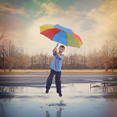Happy Boy Jumping in Rain Puddle with Umbrella