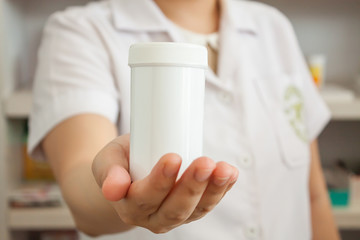 Pharmacist showing medicine bottle on her hand in the pharmacy