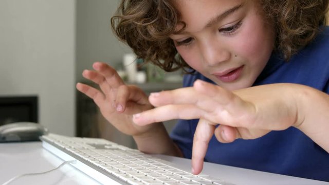 Boy typing on a white keyboard