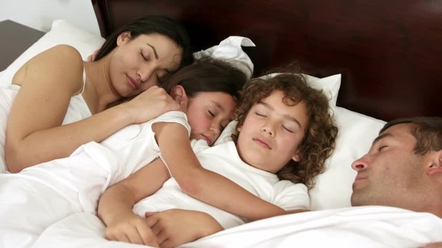 Family sleeping in the same bed