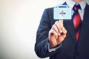 Businessman touching and pressing first aid icon in the air with one finger