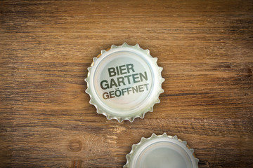 Bier-Kronkorken mit der Botschaft Biergarten Geöffnet auf alten Holz