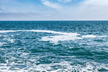 Blue sea with waves and sky with clouds