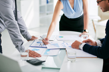 Cropped image of business people discussing papers on table