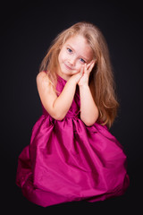 Little cute girl sitting on the floor in a pink dress