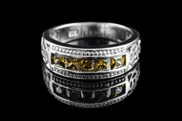 Luxury jewelry. White gold or silver engagement ring with colored gemstone closeup on black...
