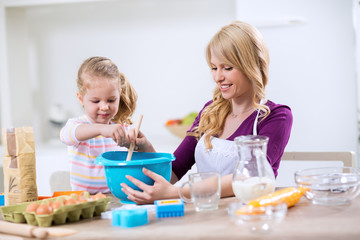 Obraz na płótnie Canvas Little girl helps mother in the kitchen