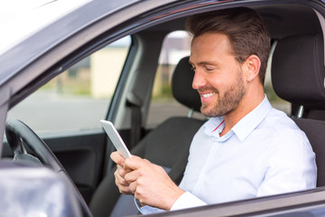 Young attractive man using mobile phone in his car