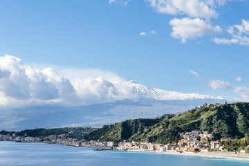 Giardini Naxos with the snowy Mount Etna in the background. Winter view from Taormina. Province of Messina. Sicily, Italy. - obrazy, fototapety, plakaty