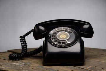 Old black phone with dust and scratches, isolated on wooden retro floor
