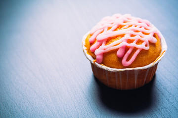 cupcake with pink frosting on a wooden background