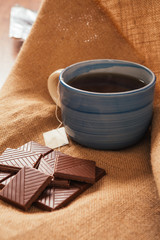blue cup of tea and a chocolate bar on background burlap