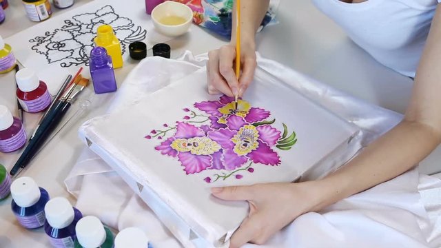 Batik Process: Artist paints on Fabric, Batik-making. Painter Draws the Floral motif on a Silk white Cloth. Handmade Beautiful Art Design. Artist Workshop with Tools, Paints and Brushes for Batik.