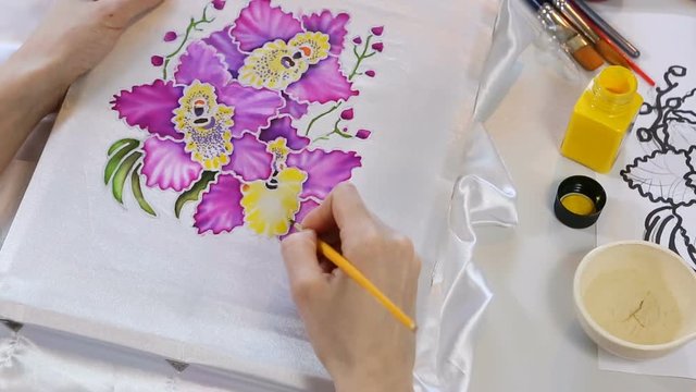 Batik Process: Artist paints on Fabric, Batik-making. Painter Draws the Floral motif on a Silk white Cloth. Handmade Beautiful Art Design. Artist Workshop with Tools, Paints and Brushes for Batik.