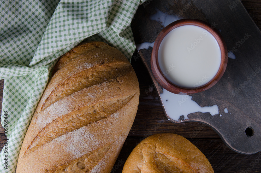 Wall mural Torn, break rustic bread with milk. Top view.