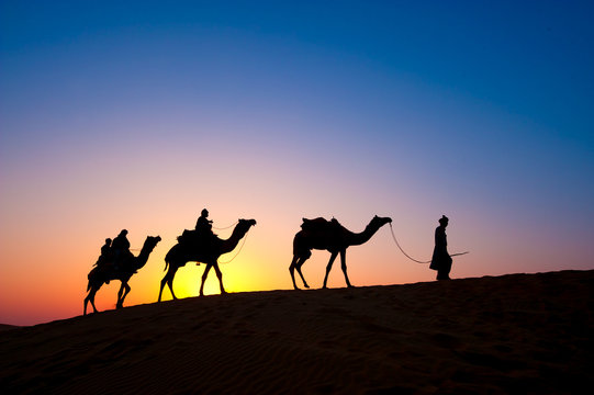Silhouette of three people on camel safari, Thar Desert National Park, Jaisalmer, Rajasthan, India
