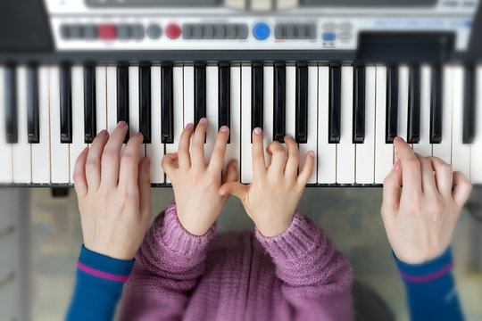 Piano Keyboard top View and Hands of Child and Mother