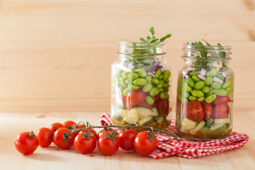 healthy vegetable salad in mason jar: tomato, cucumber, soybean,