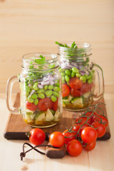 healthy vegetable salad in mason jar: tomato, cucumber, soybean,