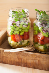 healthy vegetable salad in mason jar: tomato, cucumber, soybean,