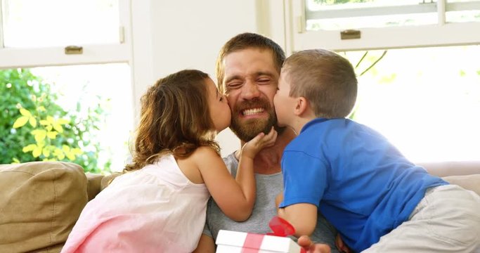 Children giving a kiss to their father