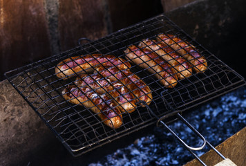 Roasting pork sausages on the grill grate over the coals 