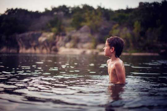 Boy standing in lake at sunset, Texas, America, USA