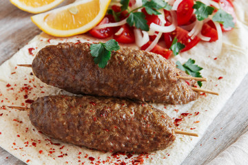 Grilled kebab meat on wooden skewers with vegetables