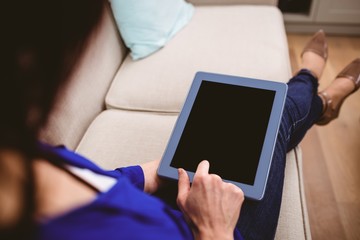 Rear view of woman using digital tablet at home