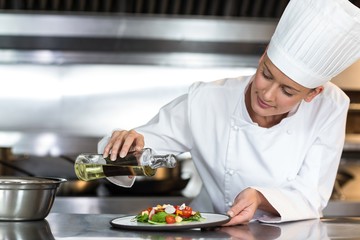 Fototapeta na wymiar Female chef pouring oil on food in plate