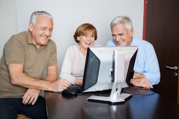 Happy Senior People Using Computer At Desk