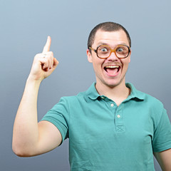 Portrait of funny nerd guy having an idea against gray backgroun