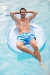 Happy shirtless man relaxing on inflatable ring