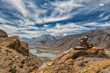 View of valley in Himalayas with stone cairn on cliff