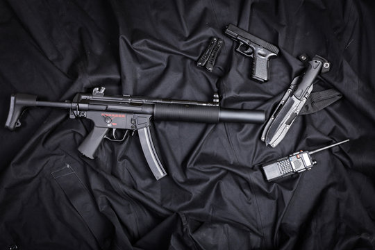 Rifle, gun, knife with sheath, compass and notebook with pen on on black cloth