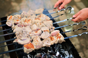 The man fries a shish kebab. Skewer just put on the grill