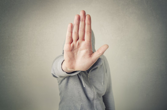 Hooded person showing stop gesture