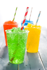 Colorful summer slushies on blue wood
