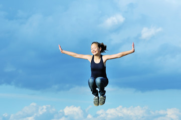 Fototapeta na wymiar beautiful girl in gymnastic jump against blue sky