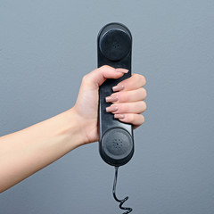 Hand holding telephone against gray background