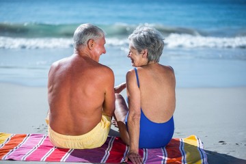 Cute mature couple sitting on a towel on the beach